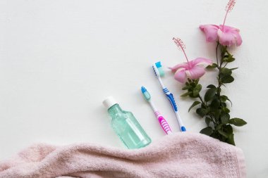 havlu kumaş, diş macunu, diş fırçası, diş macunu sağlık için arka plan beyaz tahta üzerinde pembe çiçekler ebegümeci ile ağız boşluğu