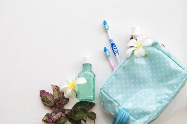 Diş macunu, diş macunu, diş fırçası sağlık için arka plan beyaz ahşap beyaz çiçekler frangipani ile mavi çanta seyahat ağız boşluğunda