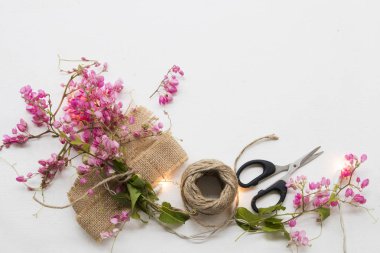 pink flowers ,rope ,scissors arrangement on sack prepare florists on background white clipart