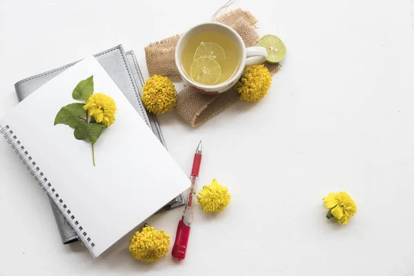 notebook planner for business work with marigold yellow flowers on sack with healthy drinks honey lemon for health care relax on background white