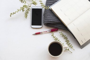cep telefonu iş için defter planlayıcısı, işe sıcak kahve ve kış sezonu ofis masası beyaz arka plan üzerinde yün atkı, örgü 