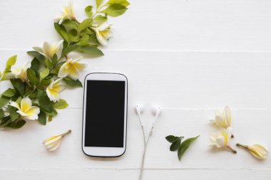 hareket eden telefon ve kulaklık ile arka plan beyaz tahta üzerinde frangipani aranjman çiçek