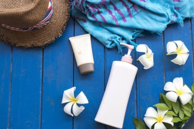 arka plan mavi ahşap beyaz çiçek frangipani spf50 güneş kremi, vücut losyonu, giyim ve yaşam tarzı kadın şapkalarına rahatlayın