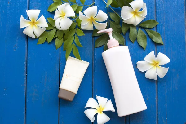 sunscreen spf50 and body lotion of lifestyle woman relax with white flower frangipani on background blue wooden