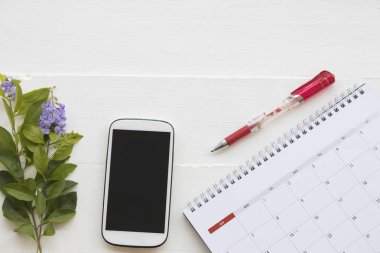 cep telefonu ve iş için Takvim Planlayıcısı ofis masası, ahşap beyaz arka plan üzerinde çiçek ile çalışmak