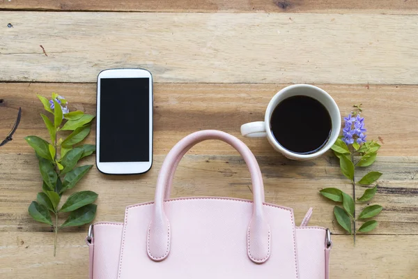 mobile phone ,hot coffee and pink hand bag of lifestyle woman relax on background wooden
