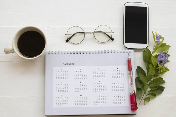 mobile phone and calendar planner for business work with flower on background wooden white at office desk