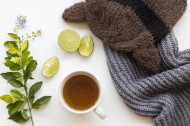 herbal honey lemon tea healthy drinks health care for sore throat with lemon slice and knitting wool scarf ,hat in winter season with purple flowers decoration on background white wooden