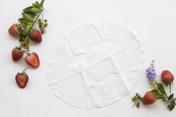 natural herbal  sheet mask aroma essence face mask extract from fruits strawberry for beauty skin face health care of woman with leaf ,flower decoration flat lay style on background white wooden