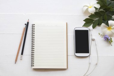 cep telefonu, dizüstü bilgisayar, öğrenci yazma Not kalem çalışma dekorasyon düz için stil arka plan beyaz tahta üzerinde yatıyordu