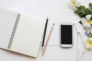 cep telefonu, dizüstü bilgisayar, öğrenci yazma Not kalem çalışma dekorasyon düz için stil arka plan beyaz tahta üzerinde yatıyordu