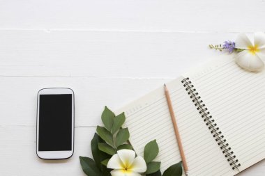 cep telefonu, dizüstü bilgisayar, öğrenci yazma Not kalem çalışma dekorasyon düz için stil arka plan beyaz tahta üzerinde yatıyordu