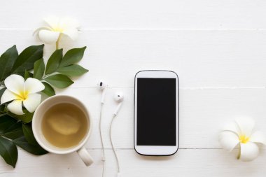 cep telefonu ve sağlıklı içecekler zencefil suyu ile çiçek frangipani çiçek dekorasyon düz stil arka plan beyaz tahta üzerinde yatıyordu