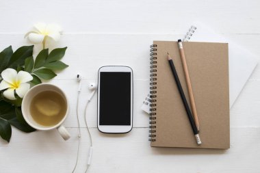 cep telefonu, dizüstü bilgisayar, öğrenci yazma Not kalem çalışma dekorasyon düz için stil arka plan beyaz tahta üzerinde yatıyordu