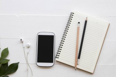 cep telefonu, dizüstü bilgisayar, öğrenci yazma Not kalem çalışma dekorasyon düz için stil arka plan beyaz tahta üzerinde yatıyordu