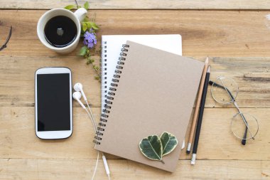 defter planlayıcısı, cep telefonu iş çalışma için sıcak kahve ve yaprak dekorasyon ile düz stil ahşap zemin üzerinde yatıyordu.