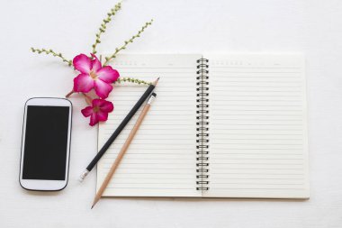 defter planlayıcısı ve cep telefonu iş için iş ile pembe çiçek dekorasyon düz beyaz arka plan üzerinde yatıyordu stili