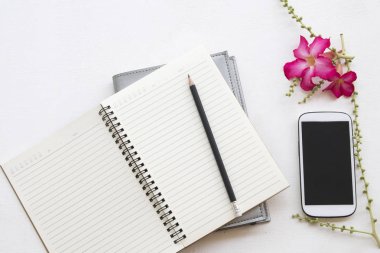 defter planlayıcısı ve cep telefonu iş için iş ile pembe çiçek dekorasyon düz beyaz arka plan üzerinde yatıyordu stili