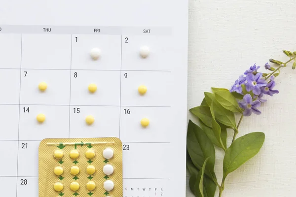 birth control pills contraceptives woman for do not want to have baby and calendar for plan  with purple flowers decoration flat lay style on background white