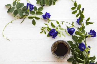 sıcak kahve Asya düzenleme düz mavi çiçek kelebek bezelye yerel florası ile stil arka plan beyaz tahta üzerinde yatıyordu