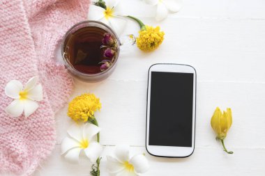 cep telefonu ve bitkisel sağlıklı içecekler sıcak gül çay kokteyl su çiçekler frangipani, kadife çiçeği, kurutulmuş gül aranjman arka plan beyaz tahta üzerinde stil yat