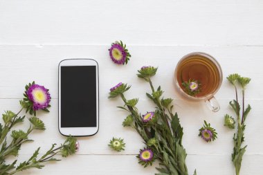 cep telefonu ve bitkisel sağlıklı içecekler sıcak limonlu çay kokteyl su mor çiçek düzenleme düz ile stil arka plan beyaz tahta üzerinde yatıyordu