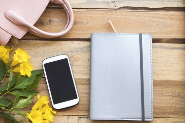 defter planlayıcısı, cep telefonu iş çalışma için yaşam tarzı kadın düzenleme düz pembe el çantası ile tarzı ahşap zemin üzerinde yatıyordu