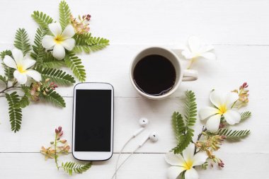 cep telefonu, sıcak kahve ve çiçek düzenleme düz arka plan beyaz tarzı yatıyordu 
