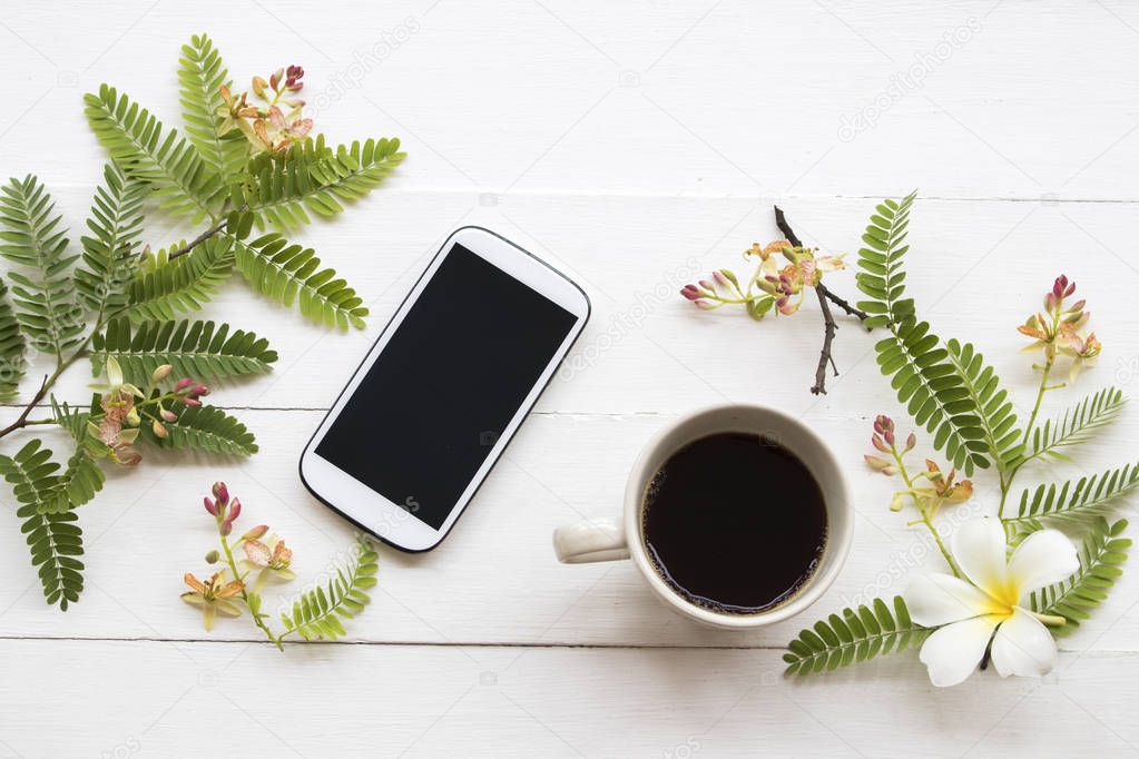mobile phone ,hot coffee and flower arrangement flat lay style on background white 