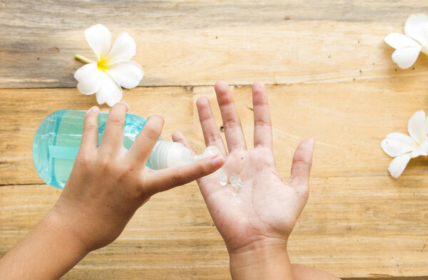 hand of girl cleaning with hand clean alcohol gel for health care hand  decoration on background wooden