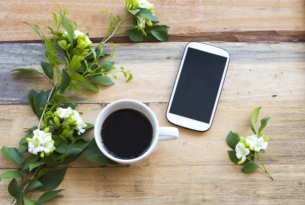 mobile phone ,hot coffee and flower jasmine of lifestyle for relaxation arrangement flat lay style on background wooden
