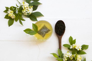 bitkisel sağlıklı içecekler ahşap kaşık ve çiçek yasemin püresi yaprak çay ile sıcak yeşil çay rahatyaşam tarzı düzenleme düz arka plan beyaz tarzı yatıyordu 
