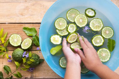 kaffir kireç dilimi bitki örtüsü ile kız temizlik eli asya su ve çiçek ve yaprak üzerinde yüzer yerel 