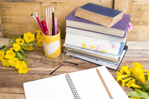 notebook ,dictionary english and all book for study of student  with stationary ,yellow flowers decoration on background wooden