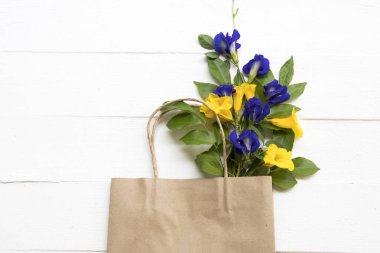 siyah çiçek kelebek bezelye ve sarı çiçek kağıt torba yerel flora asya düzenleme düz arka plan beyaz ahşap kartpostal tarzı yatıyordu
