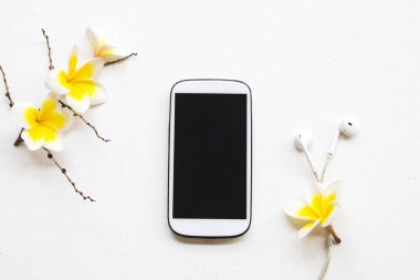 cep telefonu, kulaklık ve sarı çiçekler frangipani düzenleme düz arka plan beyaz stil yatıyordu 