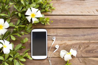 cep telefonu, çiçek frangipani ile kulaklık, arka plan ahşap yaprak düzenleme düz yatıyordu tarzı