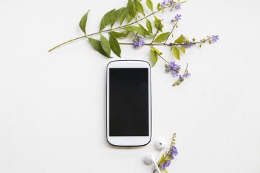 iş için cep telefonu, mor çiçekler aranjman düz ofis masasında arka plan beyaz stil yatıyordu kulaklık 