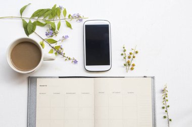iş ve mor çiçekler için cep telefonu ile dizüstü planlayıcısı, ofis masasında arka plan beyaz sıcak kahve düzenleme düz yatıyordu tarzı 