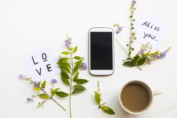 love ,miss you message card handwriting with mobile phone ,hot coffee and purple flower arrangement flat lay postcard style on background white