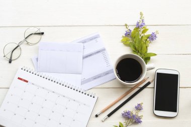 tasarruf hesabı passbook banka , kredi kartı, takvim ve cep telefonu sıcak kahve ile iş için giderleri nedeniyle, çiçek düzenleme arka plan beyaz ahşap düz yatıyordu tarzı 