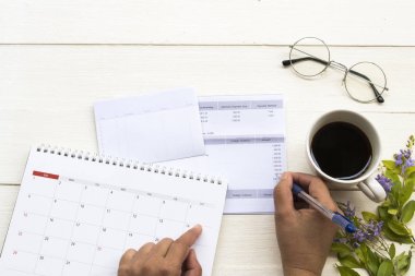 tasarruf hesabı passbook banka ile çalışan kadın eli, kredi kartı nedeniyle giderleri, sıcak kahve ile iş için takvim, ofis masasında çiçek