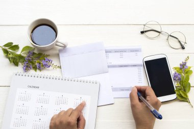 tasarruf hesabı passbook banka ile çalışan kadın eli, kredi kartı, takvim ve cep telefonu harcamaları nedeniyle sıcak kahve ile iş için, ofis masasında çiçek