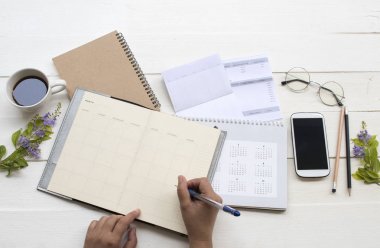 tasarruf hesabı passbook banka ile çalışan kadının el , kredi kartı, takvim, defter planlayıcısı ve cep telefonu sıcak kahve ile iş için giderleri nedeniyle ekstre , çiçekler