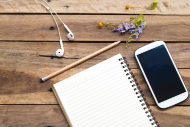 dizüstü planlayıcısı, cep telefonu ve kulaklık iş için mor çiçekler düzenleme düz ofis masasında arka plan ahşap tarzı yatıyordu