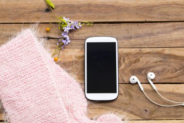 cep telefonu, kulaklık ve yaşam tarzı kadının pembe örgü yün eşarp rahatkış düzenleme düz arka plan ahşap tarzı yatıyordu