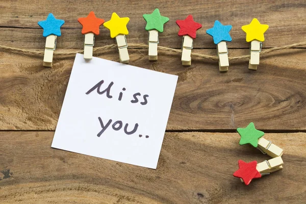 miss you message card handwriting with colorful wooden star clips arrangement flat lay postcard style on background wooden