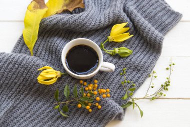 sıcak kahve espresso , örgü yün eşarp ve sarı çiçek ylang ylang, yaşam tarzı kadın sarı yaprakları sonbahar ve kış aranjmandüz arka plan beyaz stil yatıyordu dinlenmek