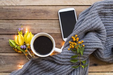 cep telefonu, sıcak kahve espresso , örgü yün eşarp ve yaşam tarzı kadın sarı çiçek ylang ylang sonbahar ve kış düzenleme düz arka plan ahşap tarzı yatıyordu dinlenmek