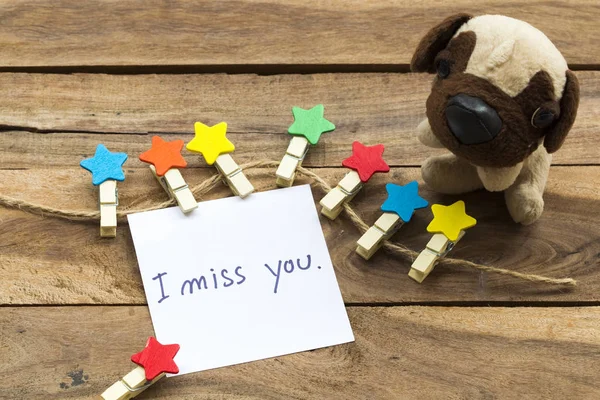 i miss you message card handwriting with colorful wooden star clips ,dog toy arrangement flat lay postcard style on background wooden